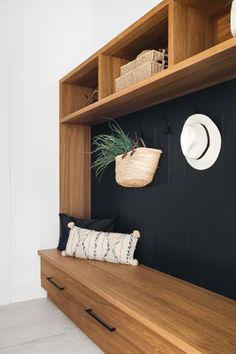 a wooden bench with two hats on it and a basket hanging from the back wall