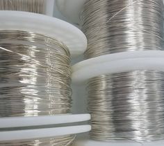 several spools of silver wire are stacked on top of each other in rows