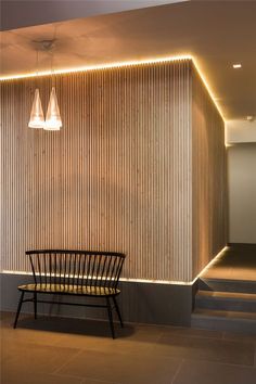 a chair sitting in front of a wall next to a stair case with lights on it