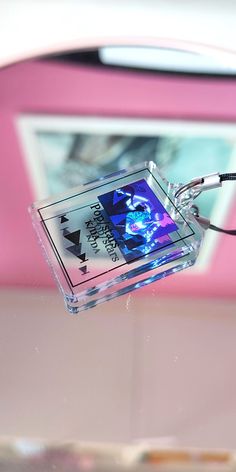 an electronic device is attached to a cord on top of a glass table in front of a pink wall