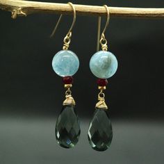 "Moss Aquamarine and Teal Quartz Earrings A stunning Teal-coloured Quartz Briolettes are dangling below large (10mm) Blue Moss Aquamarine beads accented with raspberry Ruby beads. The Briolette and The gems are wrapped with high quality 14k gold filled wire and swing from a gold filled hook. These are natural, not colourd excellent AAA quality gems, beautifuly faceted and sparkling. An elegant and feminine, chic statement earrings, perfect for special occasion, wedding, holidays or as a Gift for Flower Earrings Gold, Moss Aquamarine, Ruby Beads, Aquamarine Beads, Green Gems, Quartz Earrings, Summer Jewelry, Blue Earrings, Jewelry Gift Box