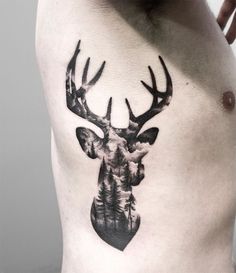 a man with a deer head tattoo on his chest is shown in black and white