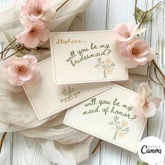 three cards with pink flowers on them sitting next to some white cloths and one has the words will you be my bridesmaid?