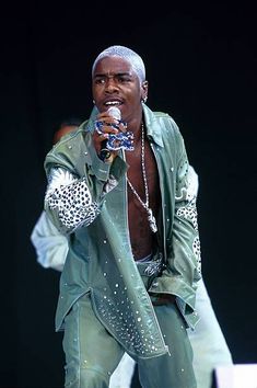 a man in a green suit holding a microphone and singing into a mic on stage