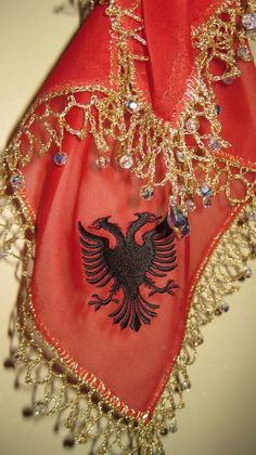 a red scarf with a black eagle on it's side and gold chains around the edges