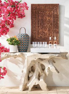 a wooden table with vases and glasses on it in front of pink bougaia