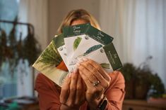 a woman holding up several seed packets in front of her face with both hands on top of them