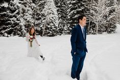 a bride and groom walking through the snow