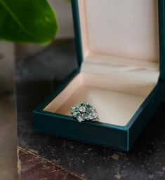 This lovely 70s Era cocktail ring features: - One .18 carat Round Brilliant cut center Diamond that is H Color and I1 Clarity  - Six emerald cut Emeralds with a combined weight of .30 carats - Eight Round Brilliant cut Diamonds with a combined weight of .15 carats, Color I Clarity I1 - 14K White Gold Ring Weight: 5.65 grams Ring has been appraised by a certified GIA Gemologist and certification is included with purchase. Ring Box is included. Vintage Emerald Ring With Brilliant Cut For Gift, Emerald Cluster Ring With Brilliant Cut As Gift, Cluster Ring As May Birthstone Gift, Vintage Emerald Cut Emerald Ring As Gift, Vintage Emerald Cut Emerald Ring For Gift, Vintage Emerald Cluster Ring As Gift, Vintage Emerald Cluster Ring As A Gift, Emerald Cluster Ring With Brilliant Cut For Gift, Gift Emerald Cluster Ring With Brilliant Cut