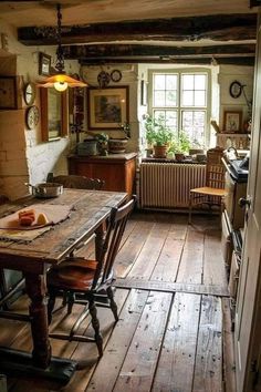 an old fashioned kitchen with wood flooring and wooden table in front of a window