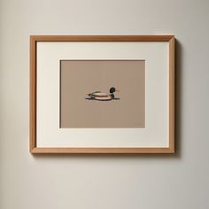 a duck floating on top of a body of water next to a wall with a wooden frame