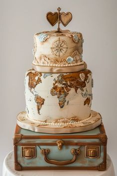 a three tiered cake with a world map on top and two hearts atop it