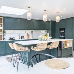 a kitchen with green cabinets and bar stools next to an island in the middle