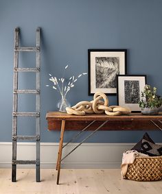 a wooden table topped with lots of bread next to a ladder and pictures on the wall