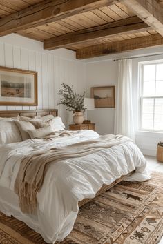 a large bed sitting in a bedroom next to a window with wooden beams on the ceiling