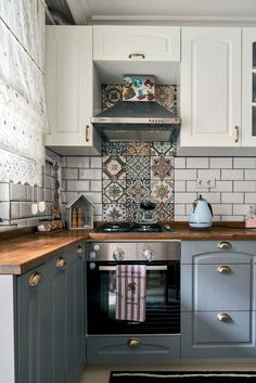 a stove top oven sitting inside of a kitchen next to a wooden countertop and white cabinets