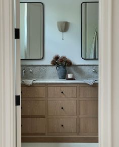 a bathroom with two sinks and mirrors on the wall next to an open door that leads to another room