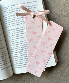 an open book with pink hearts and bows on it next to a pair of scissors