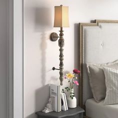 a bedroom with a bed, nightstand and lamp on the side table in front of it