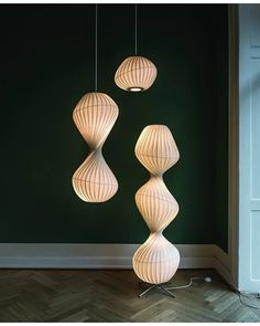 three lamps hanging from the ceiling in a room with green walls and wood flooring