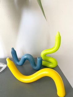 two yellow and blue plastic objects sitting on top of a table next to a plant