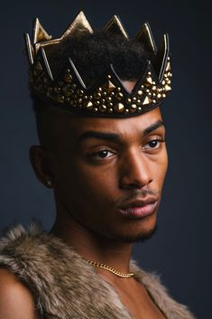 a man with a crown on his head and fur vest around his neck is looking at the camera