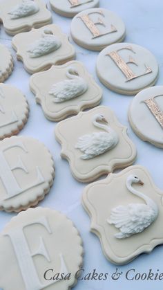 decorated cookies are arranged on a table with the letters e, f, and swans