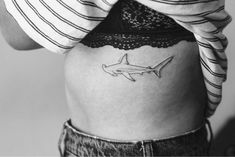 a black and white photo of a woman's stomach with a shark tattoo on it