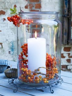 a candle is lit in a glass jar filled with berries