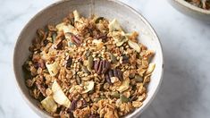 two bowls filled with granola on top of a white countertop next to each other