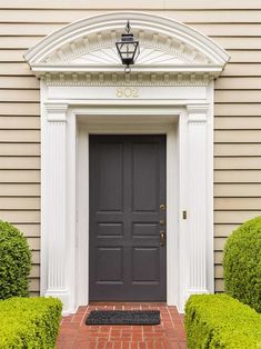 the front door is flanked by two trimmed bushes