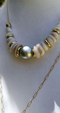 a necklace with white and gold beads on a mannequin