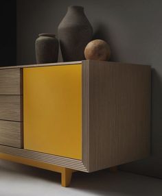 a yellow cabinet with two vases on top and another one in the back ground