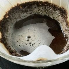 a bowl filled with brown liquid and dirt on top of a stovetop burner