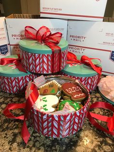 four boxes with decorated cookies and candies in them on a counter top next to some wrapped presents