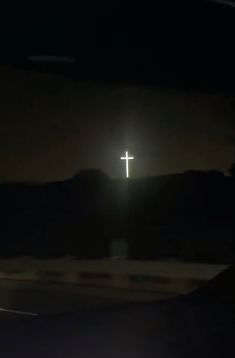 the cross is lit up in the dark sky