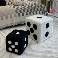 two black and white dice sitting on top of a floor next to a bed in a bedroom