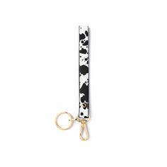 a black and white cow print keychain hanging from a gold - tone metal hook