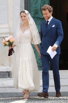 the bride and groom are holding hands as they walk out of the church door together