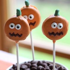 two pumpkin shaped lollipops sitting on top of chocolate chips in a bowl