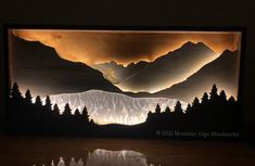 an image of mountains and trees lit up in the dark with light coming from them