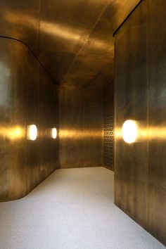 an empty room with gold colored walls and round lights on the wall, as well as white carpet