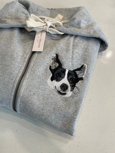 a grey sweatshirt with a black and white dog embroidered on it