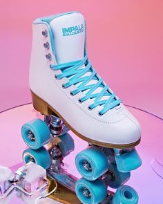 a pair of roller skates sitting on top of a glass table in front of a pink background