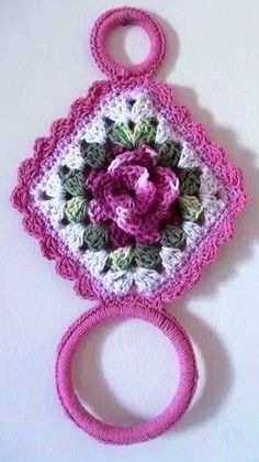 a pink crocheted object with a flower on it's center and two circular handles