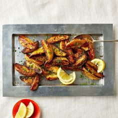 there is a tray that has some fried food on it with lemons and parsley