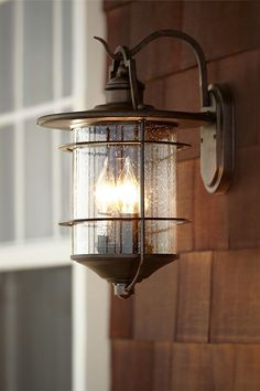 an outdoor light hanging from the side of a house