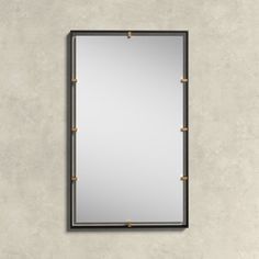 a mirror hanging on the wall with gold studded trimmings and a black frame