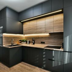 a kitchen with black cabinets and wood flooring is pictured in this image, there are lights above the sink