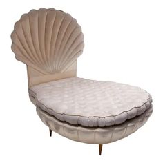 an upholstered chair with a shell shaped backrest and foot rest on it